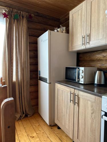 cocina con nevera blanca y armarios de madera en Cottage Marko, en Lazeshchyna