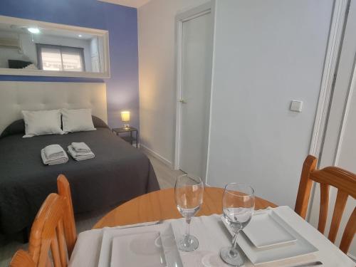 Habitación con cama y mesa con copas de vino en ESTUDIO en TORREMOLINOS, PLAZA DE ANDALUCIA, en Torremolinos
