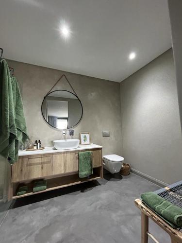 a bathroom with a sink and a mirror and a toilet at Spacious Beach Breakaway in Groot Brak Rivier