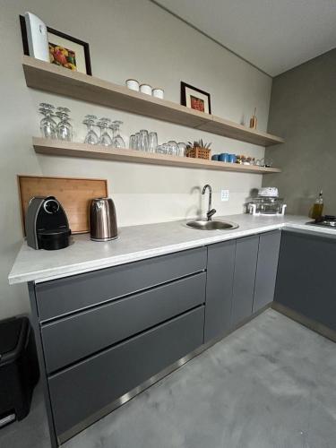a kitchen with a sink and a counter with shelves at Spacious Beach Breakaway in Groot Brak Rivier