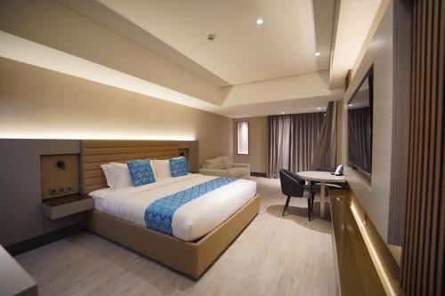マニラにあるBayprime Hotelのベッドとデスクが備わるホテルルームです。