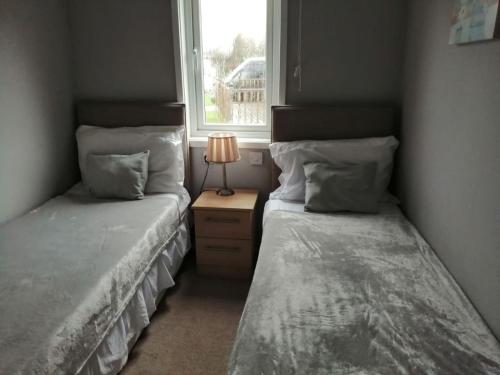 2 Einzelbetten in einem Zimmer mit Fenster in der Unterkunft Carnoustie Lodge in Wisbech