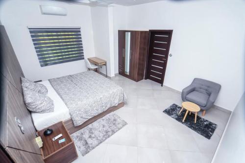 a small bedroom with a bed and a chair at RESIDENCE MH SERVICES Cotonou in Cotonou
