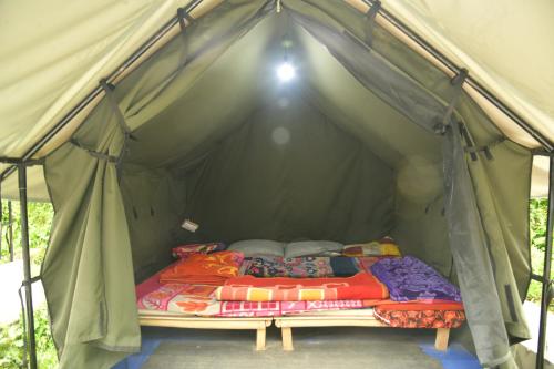 a bed in a green tent at Himtrek Riverside Camps, Kasol in Kasol