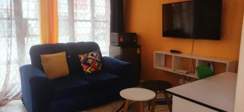 ein Wohnzimmer mit einem blauen Stuhl und einem TV in der Unterkunft Racecourse Gardens Apartment in Nairobi