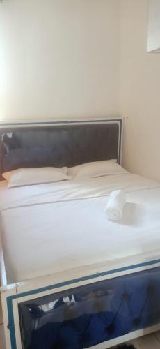 ein leeres Bett in einem Raum mit gedankenlosem, gedankenlosem, gedankenlosem, gedankenlosem in der Unterkunft Racecourse Gardens Apartment in Nairobi