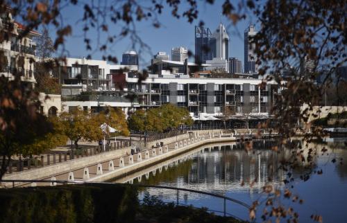 a bridge over a river with a city in the background at East Perth Suites Hotel in Perth