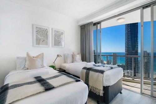two beds in a hotel room with a large window at 3 Bedroom Apartment with Ocean Views in Central Location - Chevron Renaissance - Wow Stay in Gold Coast