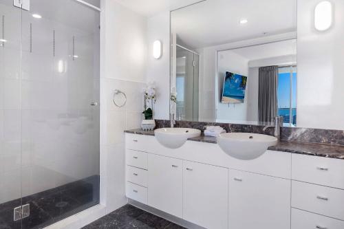 a white bathroom with two sinks and a shower at 3 Bedroom Apartment with Ocean Views in Central Location - Chevron Renaissance - Wow Stay in Gold Coast
