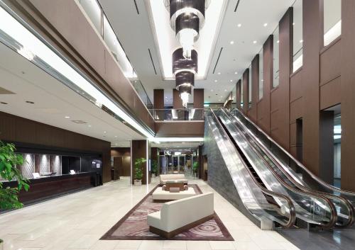 a lobby with an escalator in a building at Palace Hotel Omiya in Saitama