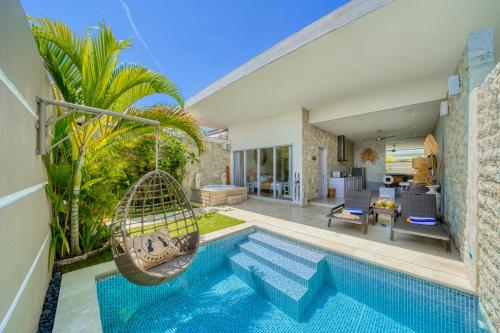 a swimming pool with a swing and a house at Bali Cosy Villas Seminyak in Legian
