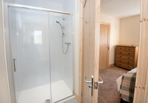Un baño con ducha con puerta de cristal. en Rockpool, en Pollachar