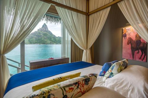 a bedroom with a bed with a view of the water at InterContinental Bora Bora & Thalasso Spa by IHG in Bora Bora