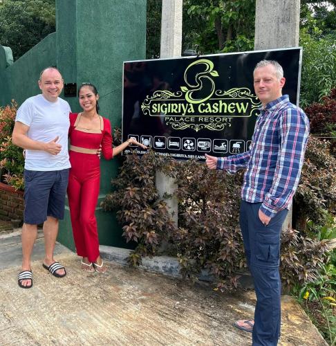 two men and a woman standing in front of a sign at Sigiriya Cashew Palace Resort in Sigiriya