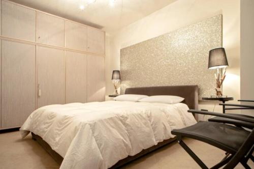 a bedroom with a white bed and a black chair at Appartamento nuovo 6 posti - Abetone in Abetone
