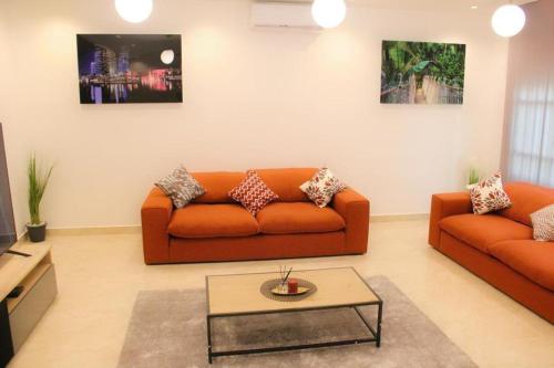a living room with two orange couches and a coffee table at RESIDENCE MH SERVICES Cotonou in Cotonou