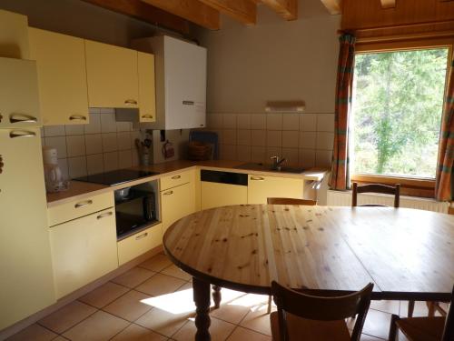 una cucina con tavolo in legno e tavolo e una sala da pranzo di Chalet Beaujon Chapelle-des-Bois a Chapelle-des-Bois