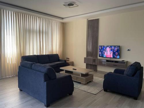 a living room with two blue couches and a tv at Modern living in Addis Ababa