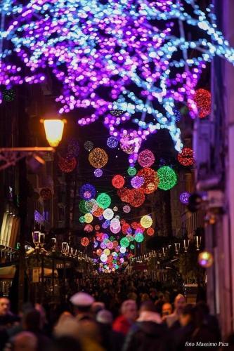 a crowd of people walking down a street with christmas lights at The Secret Garden in Salerno