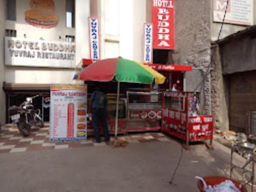 a person standing next to a hot dog stand with an umbrella at Hotel Buddha,Gaya in Bodh Gaya