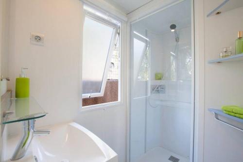 a white bathroom with a shower and a sink at Camping Le Gallo Romain in Barbières