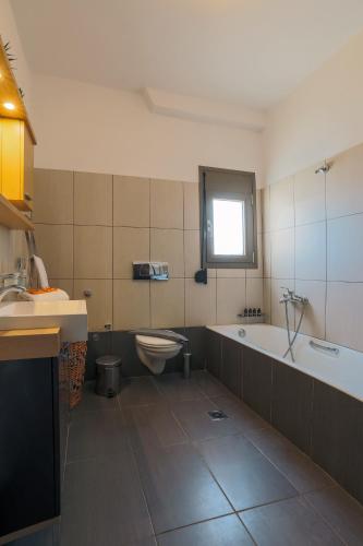 a bathroom with a tub and a toilet and a sink at Malena in Karavomylos