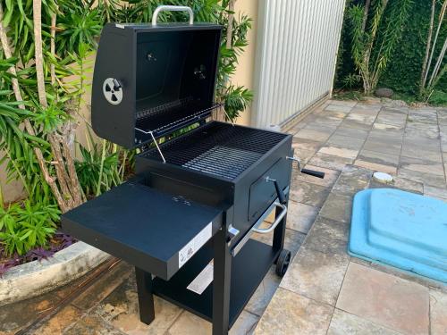 a bbq grill with a blue stool next to it at Casa 3 suítes com piscina in Natal