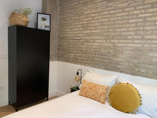 Un dormitorio con una pared de ladrillo y una cama en La Reina Beach rooms, en Valencia