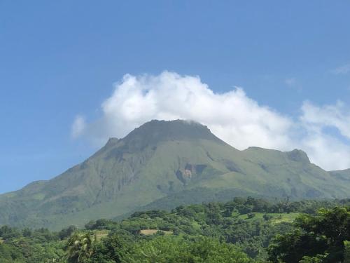 a mountain with clouds on top of it at Les Frangipaniers de la Pelée in Saint-Pierre
