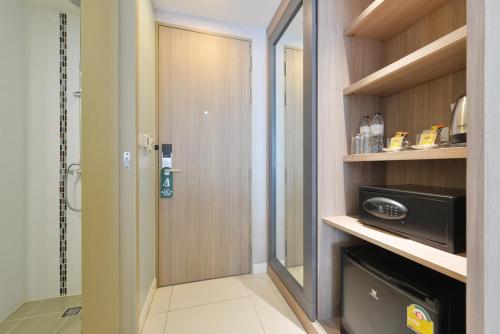 a bathroom with a walk in shower and a microwave at Grace Patong Hotel in Patong Beach