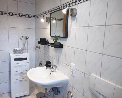 a white bathroom with a sink and a mirror at Ferienwohnung Hilderser Auszeit in Hilders