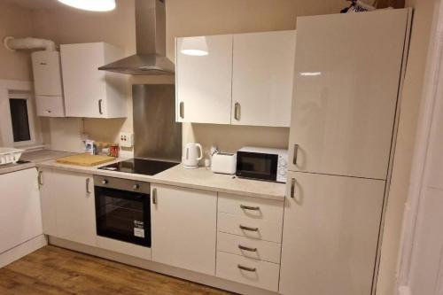 a kitchen with white cabinets and a white refrigerator at Archillects - Entire Two Bedroom Comfy House in Glasgow