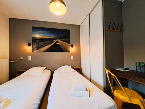 two beds in a room with a picture on the wall at Hôtel Les Mouflons in Le Mont-Dore