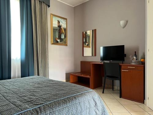 Habitación de hotel con cama, escritorio y TV. en Hotel Ristorante Cervo Malpensa, en Case Nuove