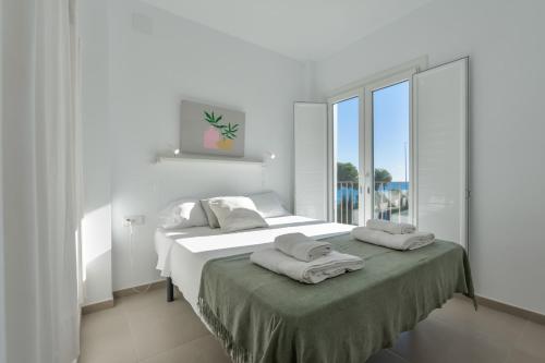 a white bedroom with two beds and a large window at Bianca - by Almarina Villas in Teulada