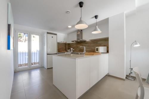 a white kitchen with a counter and a sink at Bianca - by Almarina Villas in Teulada