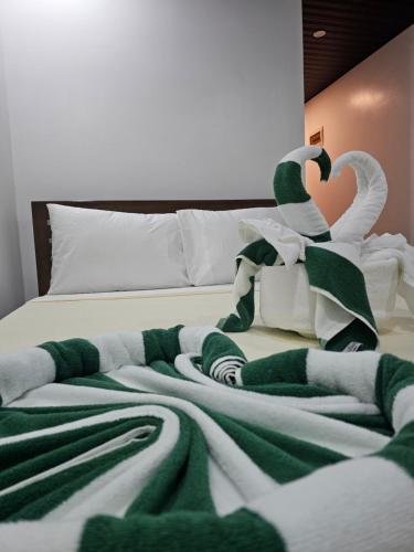 a bed with green and white blankets and swans on it at Cocoloco Beach Resort in Boracay