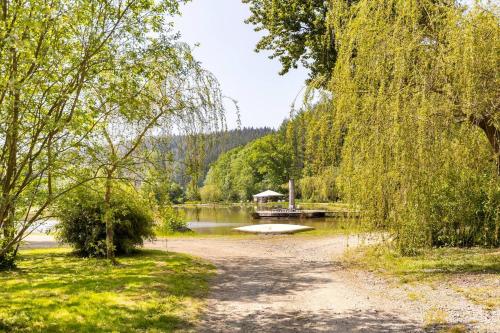 a path in a park with a lake and a dock at Tinyhouses - Domain "La vallée des Prés" in Bande