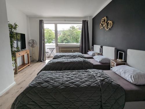 a hotel room with three beds and a window at Downtown Apartments Unterbilk in Düsseldorf