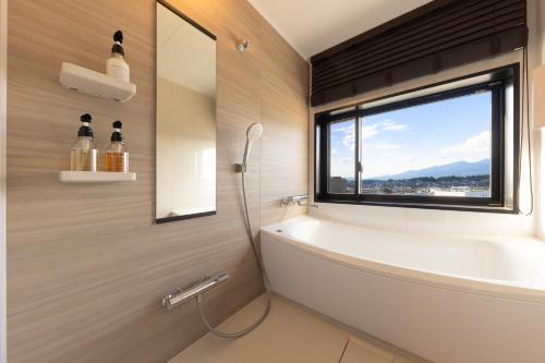 baño con bañera y ventana en AQA Hotel Premium en Saku