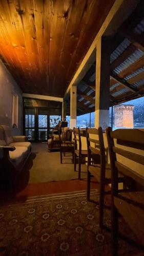 a living room with chairs and a couch and windows at Guesthouse Chela in Mestia