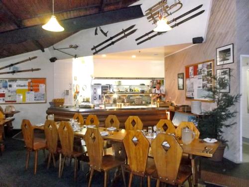 a dining room with a table and chairs and a kitchen at Sundeck Hotel in Perisher Valley