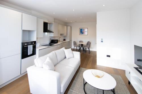 Sala de estar blanca con sofá blanco y mesa en Ealing Residency, en Londres