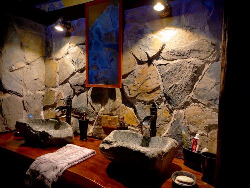 baño con 2 lavabos y pared de piedra en Explore - Cozzy Cabin Located in Duhatao, Chiloe Island, Patagonia, Chile, en Ancud