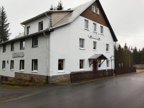 un gran edificio blanco con techo de gambrel en Pension Waldhaus, en Eibenstock