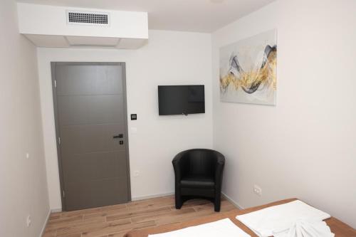 Zimmer mit einem schwarzen Stuhl und einem TV an der Wand in der Unterkunft Swiss Apartmani in Banja Luka
