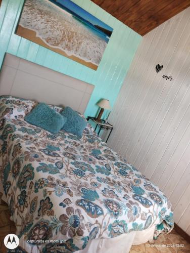 1 dormitorio con 1 cama con colcha de flores en Complejo Elementos en Colonia Chapadmalal