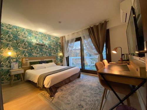 a bedroom with a bed and a desk and a window at Savoie Hotel aux portes de Genève in Saint-Julien-en-Genevois