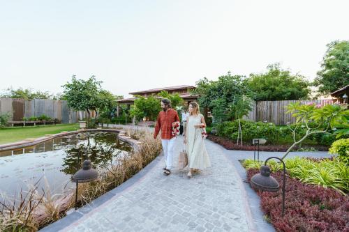 a bride and groom walking down a path in front of a pond at Surpura Bagh - A Luxury Boutique Resort in Jodhpur