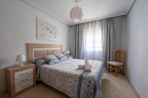 a bedroom with a bed and a chair and a window at Sevilla Sol in Seville